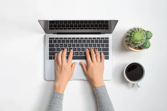 Hände tippen auf einer Laptoptastatur.